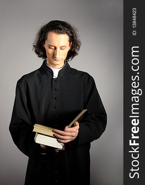 Conceptual portrait of Praying priest with wooden cross reading Holy Bible. yellow background