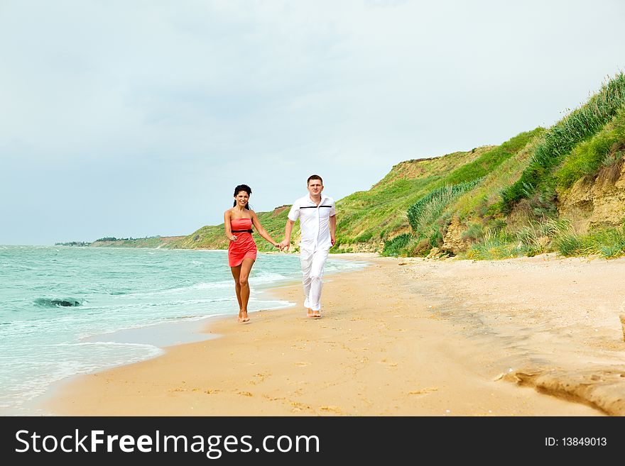 Lovely happy couple running along the beach