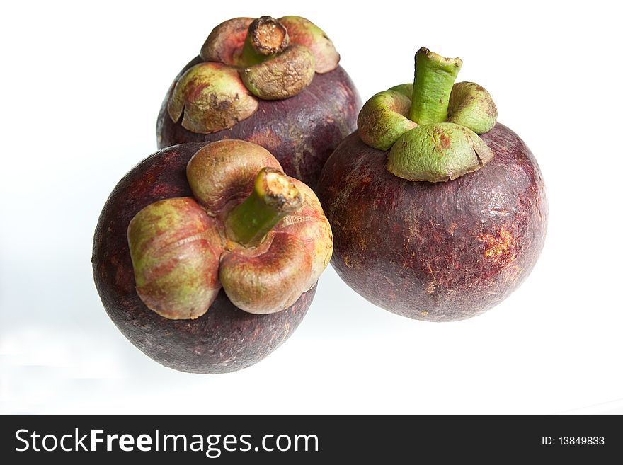 Three mangosteens isolated against a white background