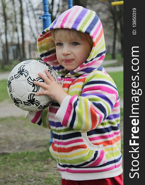 A child on a walk playing with the ball