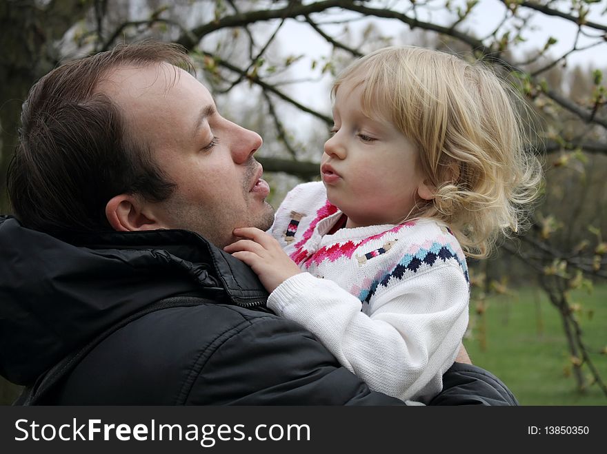 Dad keeps daughter in his arms for a walk in the park. Dad keeps daughter in his arms for a walk in the park