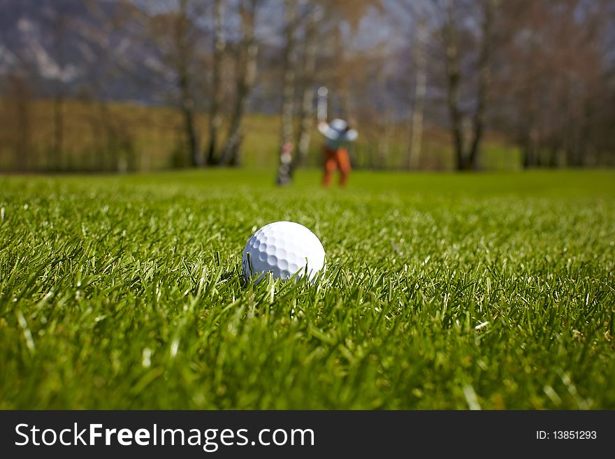 Golf ball close-up with golfer man at the background