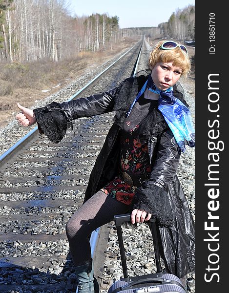 Funny pictures, jokes, hitchhiking on the railroad, blonde woman with a suitcase catches a passing train as the car hitchhiking, a woman standing with arms raised. Funny pictures, jokes, hitchhiking on the railroad, blonde woman with a suitcase catches a passing train as the car hitchhiking, a woman standing with arms raised