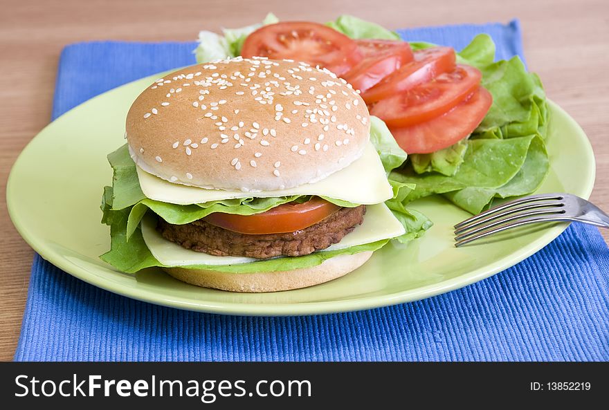 Fresh cheeseburger with lettuce, tomato and mayo and vegetables on the side. Fresh cheeseburger with lettuce, tomato and mayo and vegetables on the side