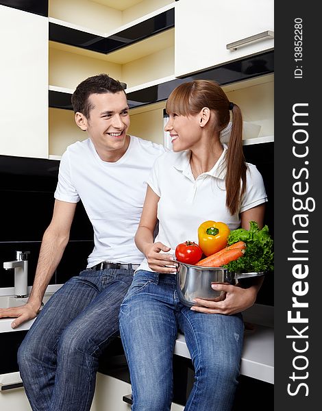 Smiling couple with capacity with vegetables on kitchen. Smiling couple with capacity with vegetables on kitchen