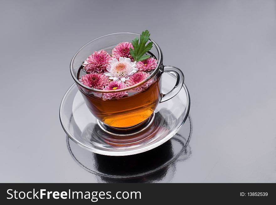 Cup of herbal tea with flowers on black glossy background