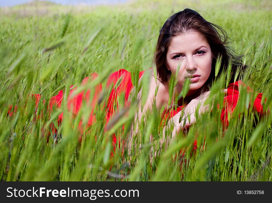 Young beautiful woman in red dress lying on the field. Young beautiful woman in red dress lying on the field