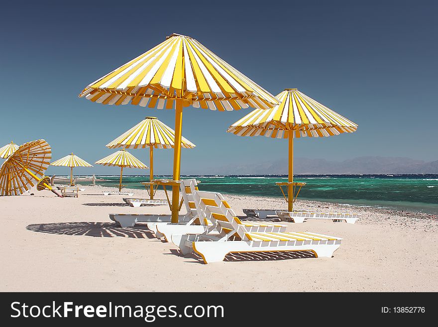 Umbrellas with chairs on beach under blue sky