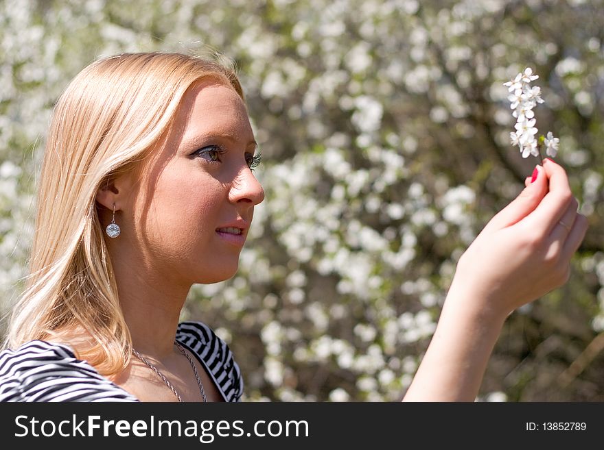 Blond girl in front of blossomed tree on early spring