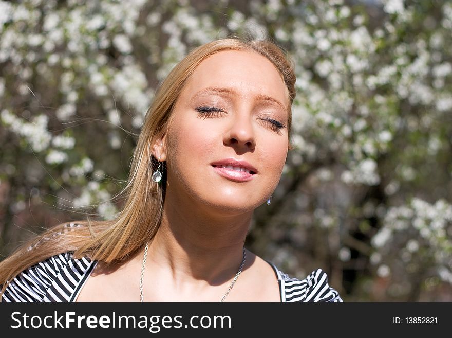 Blond girl in front of blossomed tree on early spring