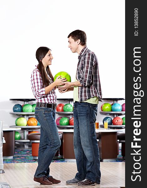 The young man gives a sphere for bowling to the girl. The young man gives a sphere for bowling to the girl