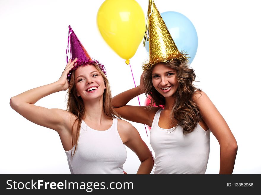 Two young girlfriends in holiday caps with color balloons. Two young girlfriends in holiday caps with color balloons