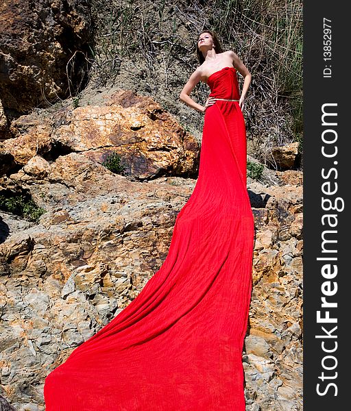 Woman in red dress from material and rocks