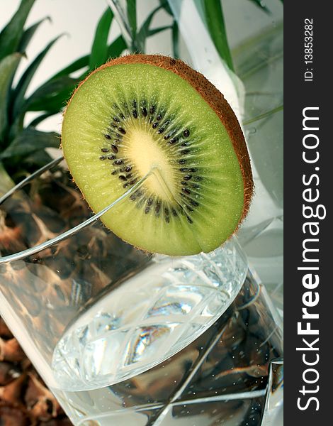 A slice kiwi with mineral water , pineapple background