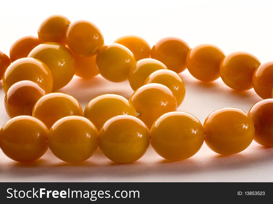 Amber chaplet being shoot in macro with sparkles of light on the beads isolated on the white background. Amber chaplet being shoot in macro with sparkles of light on the beads isolated on the white background