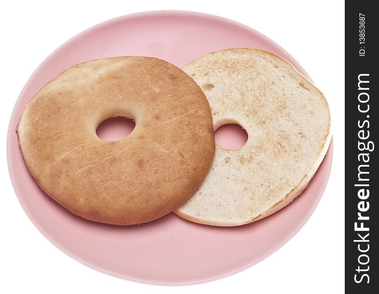 Toasted bagel on a pink plate isolated on white with a clipping path. Toasted bagel on a pink plate isolated on white with a clipping path.