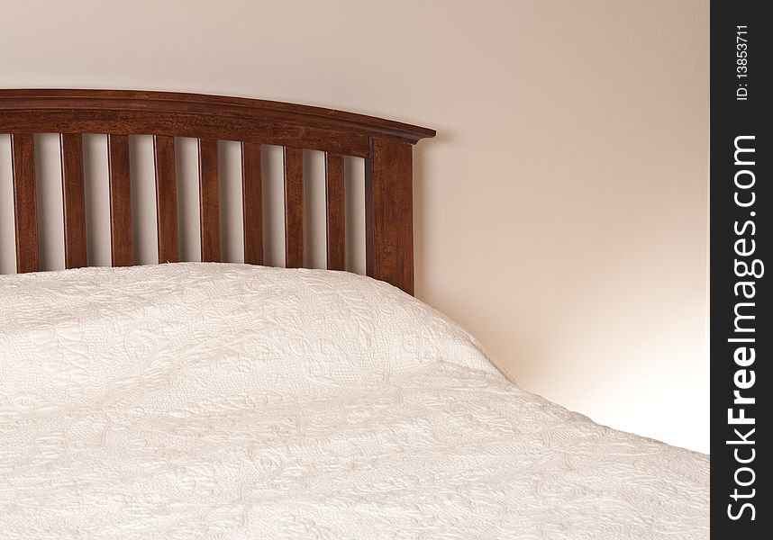 Bedroom Interior with Wooden Freshly Made Bed, and Neutral Wall and Linens.