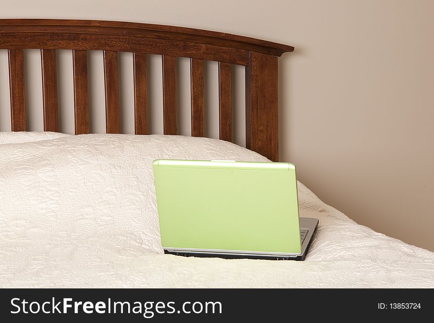 Working from home with a green laptop computer on a bed.