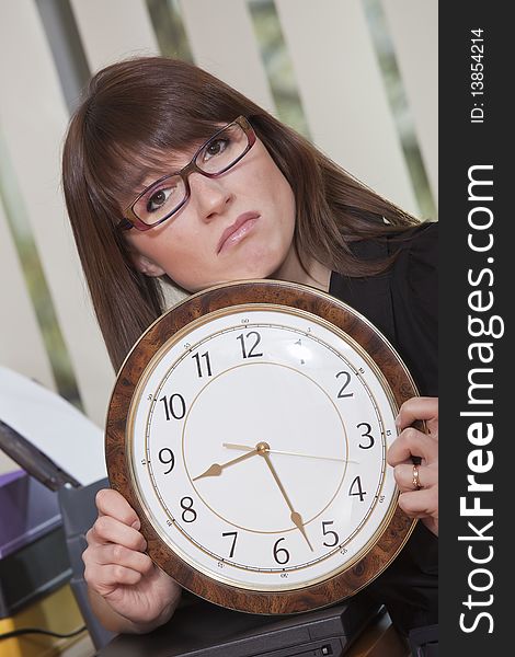 Unhappy business woman holding big watch in office. Unhappy business woman holding big watch in office