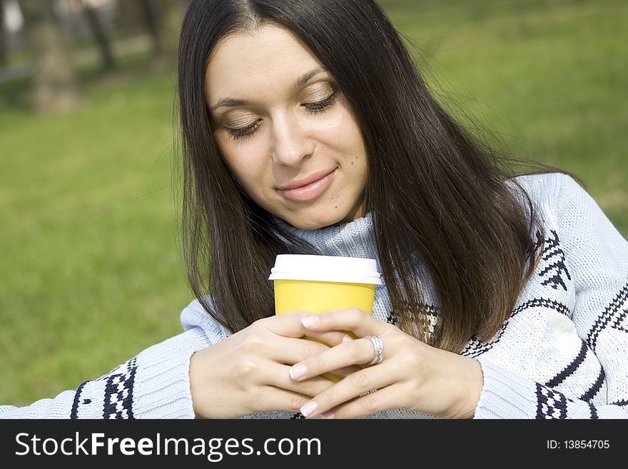 Beautiful girl in a park drinking coffee