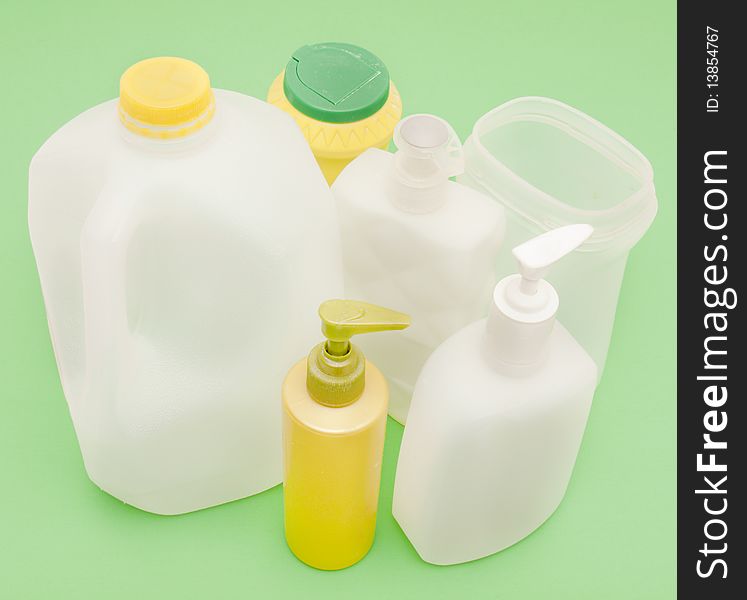 Overhead shot of used plastic containers on green background to suggest recycling, environmental awareness. All labels, logos, etc. have been removed. Overhead shot of used plastic containers on green background to suggest recycling, environmental awareness. All labels, logos, etc. have been removed.