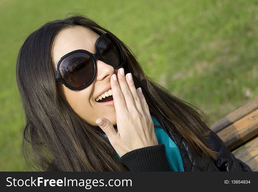 Surprised beautiful woman in the park laughs and covers his mouth with his hand. Surprised beautiful woman in the park laughs and covers his mouth with his hand