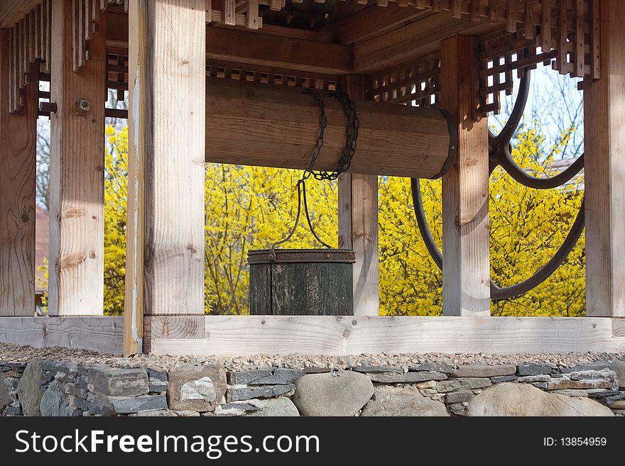 Old well with spring yellow blossom on background