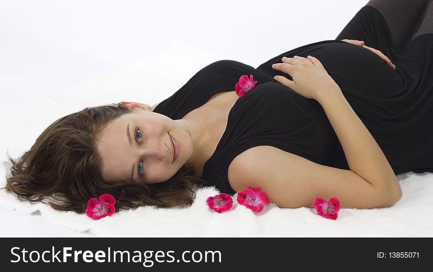 Beautiful young pregnant woman lying with flowers. Beautiful young pregnant woman lying with flowers