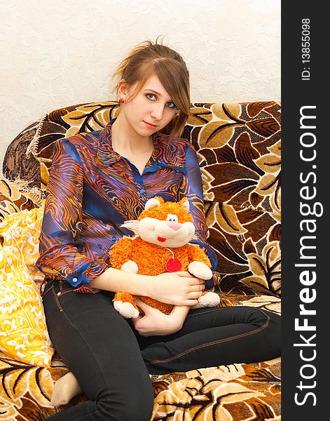 The constraining girl sits on a sofa with a toy