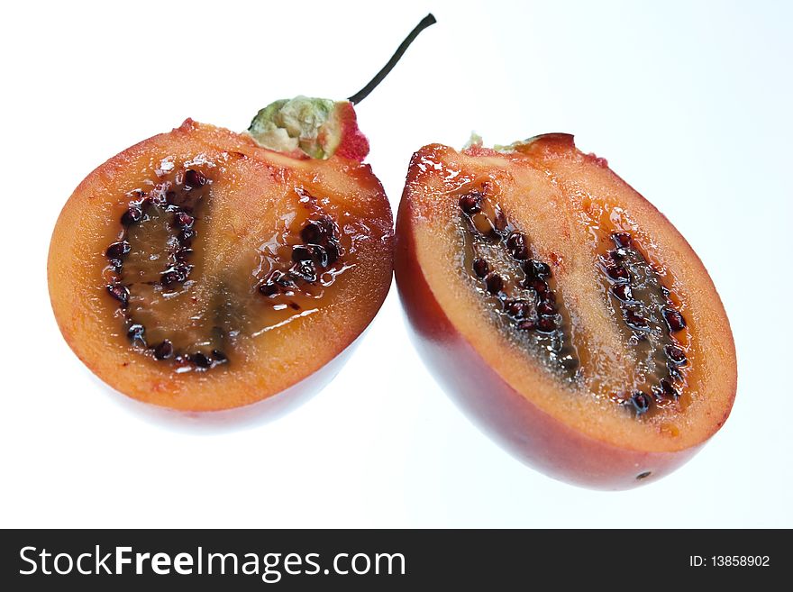 A tamarillo cut in half and isolated against a white background. A tamarillo cut in half and isolated against a white background