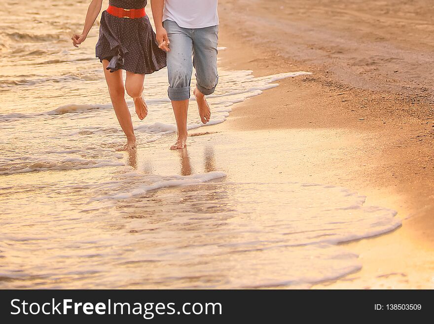 Couple in love runs barefoot on the sea along the surf at sunset. honeymoon, valentine, happiness and love