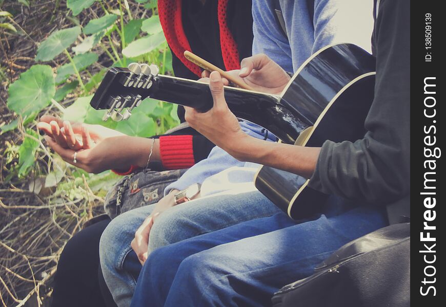 Friends playing guitar in park
