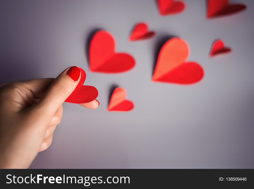 A woman`s hand holds a red heart .valentines day Card. A woman`s hand holds a red heart .valentines day Card