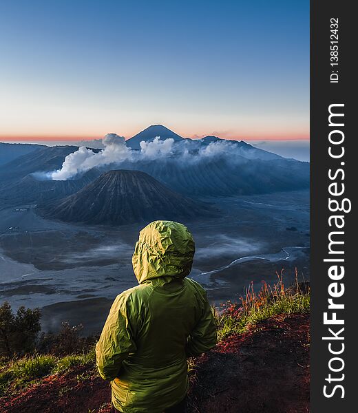 Hiker watches view of Mount Bromo during sunrise on Java, Indonesia. Hiker watches view of Mount Bromo during sunrise on Java, Indonesia