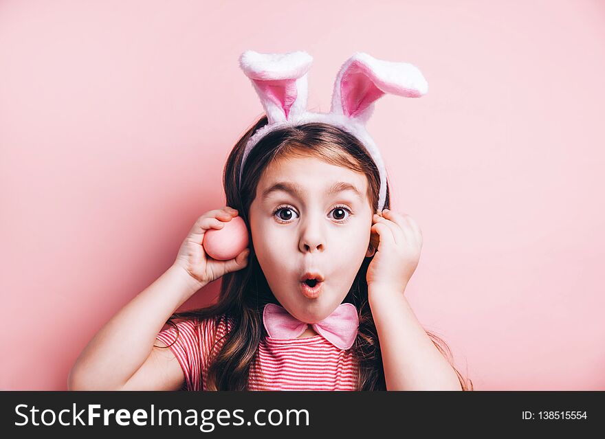 Cute little girl with bunny ears on pink background.