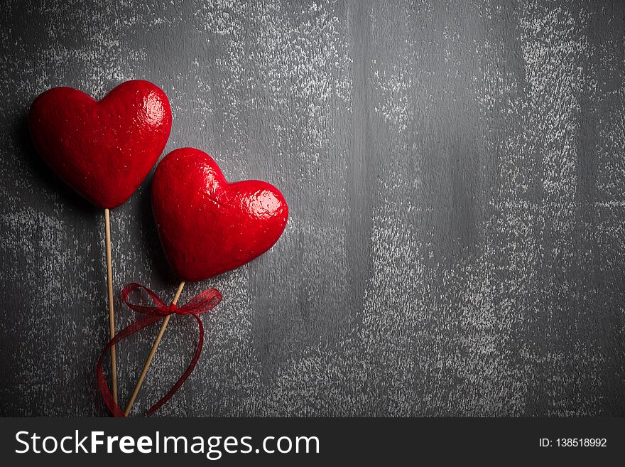 Valentines day and love concept. Two handmade red hearts with red ribbon on gray wooden background