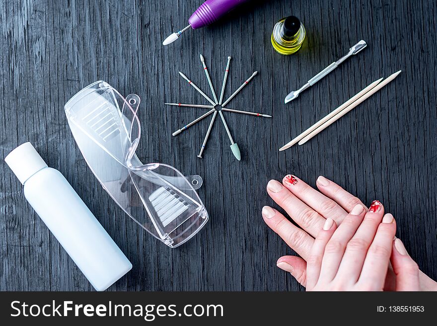 Tools for professional hardware manicure and women`s hands with manicure on dark background. Tools for professional hardware manicure and women`s hands with manicure on dark background
