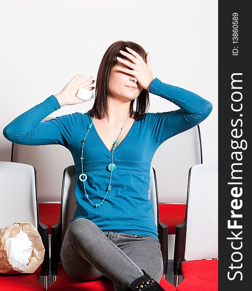 Scared young woman sitting and covering her eyes with hand while watching movie, holding tissue, vertical shot. Scared young woman sitting and covering her eyes with hand while watching movie, holding tissue, vertical shot