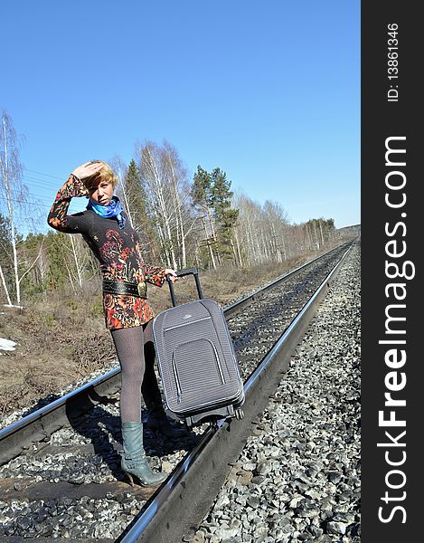 Young woman defends her hand face of the sun, with blonde hair and carries a bag on the tracks, the bright sun. Young woman defends her hand face of the sun, with blonde hair and carries a bag on the tracks, the bright sun