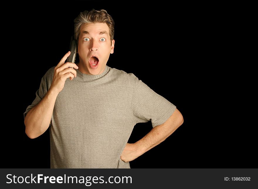 Man using a phone looking surprised on a black background