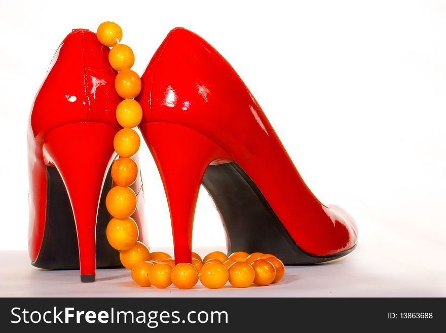 Red shoes and amber collar or chaplet isolated on the white background