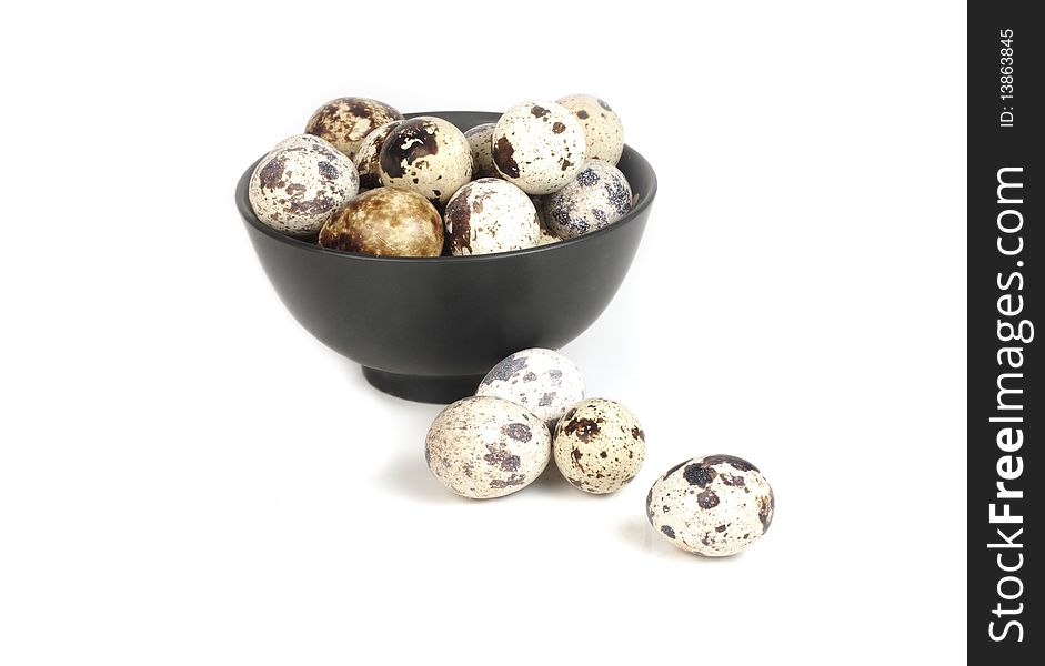 Quail eggs in a bowl of black on a white background