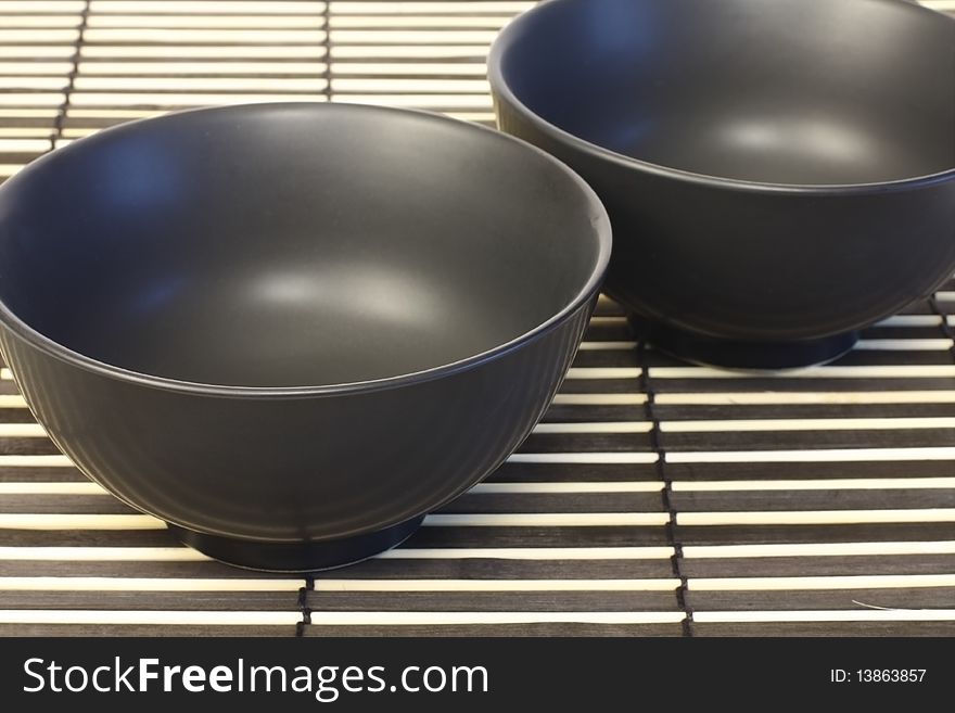Two black bowls on a wooden panel. Two black bowls on a wooden panel