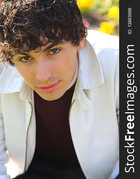 Curly haired young adult man in white, outdoor portrait