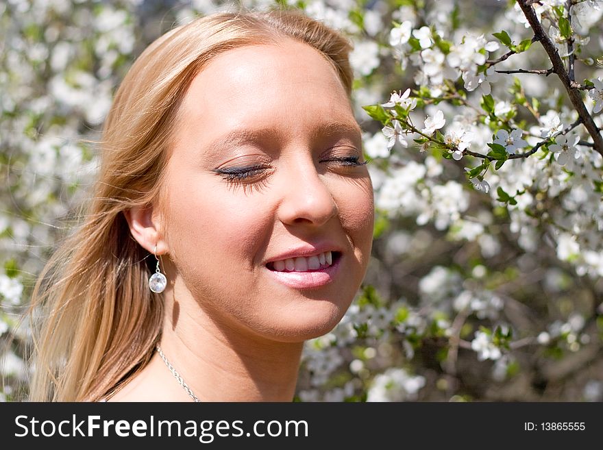 Blond girl in front of blossomed tree on early spring