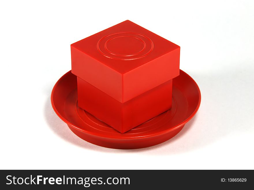 Red cube on a red saucer on a white background