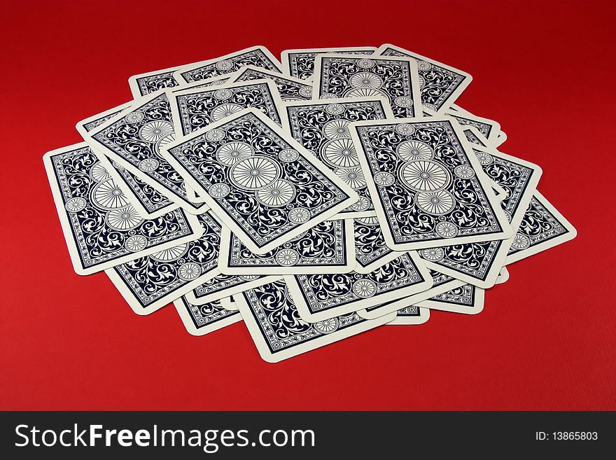 The scattered dark blue playing cards on a red background. The scattered dark blue playing cards on a red background