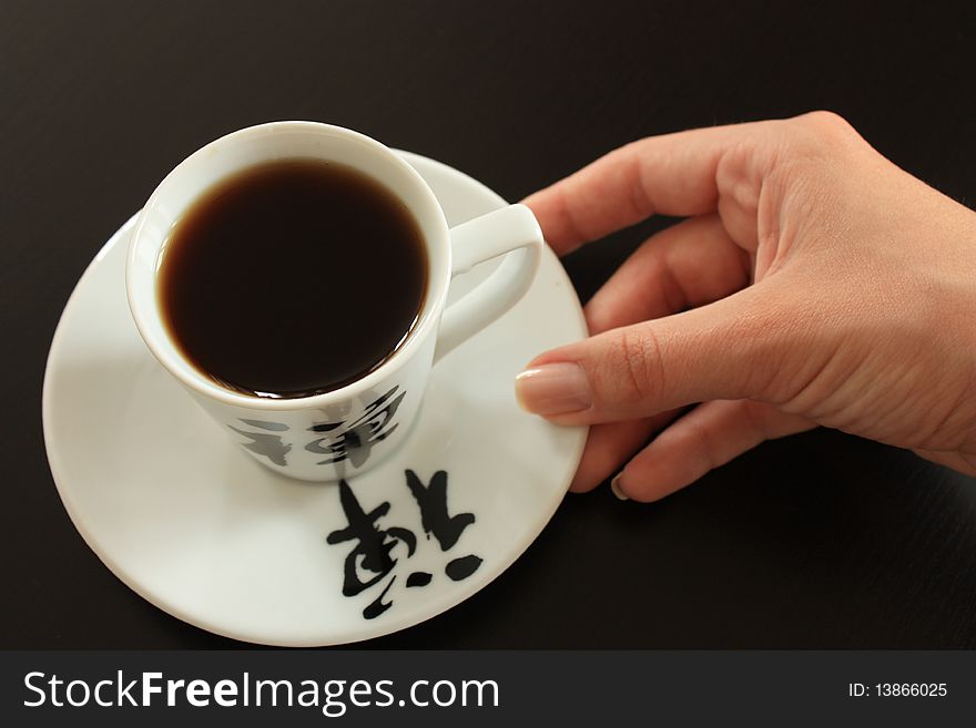 Coffee cup and saucer with hieroglyph on dark wooden background, selective focus