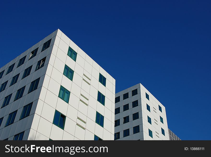 Two white office buildings with a blue sky