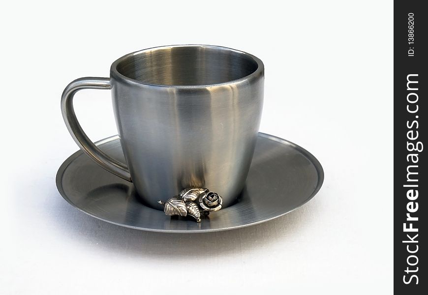 A cup of silver metal and a beautiful brooch. A cup of silver metal and a beautiful brooch